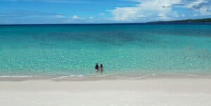 Pareja de viajeros por el mundo disfrutando de una playa paradisíaca en Filipinas con aguas cristalinas de color azul turquesa, ideal para vacaciones románticas