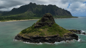 Vista panorámica de una playa paradisíaca en Hawái, con aguas turquesas y un volcán activo en el horizonte, rodeado de un paisaje volcánico único y exuberante vegetación tropical