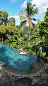 Pareja relajándose y disfrutando de un desayuno flotante en Bali, rodeados de aguas cristalinas y un ambiente tropical, ideal para una experiencia romántica en la isla