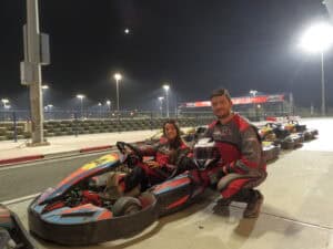 Pilotos compitiendo en una emocionante carrera de karts en Bahréin, en un circuito de alta velocidad rodeado de un paisaje desértico y moderno.