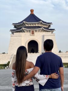 Pareja explorando las calles de Taipei, con un fondo lleno de arquitectura asiática tradicional, templos y luces de neón que capturan la esencia cultural de la ciudad
