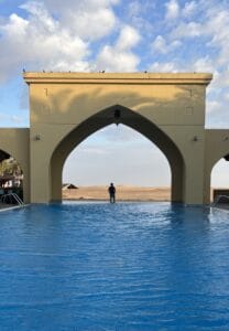 Pareja disfrutando de una aventura en el desierto de Abu Dabi, rodeados de dunas doradas y un paisaje árido impresionante, ideal para viajes de aventura y exploración