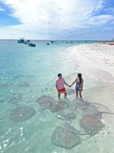 Pareja disfrutando de una experiencia única en Maldivas, nadando junto a rayas en sus aguas cristalinas, rodeados de un paisaje tropical impresionante