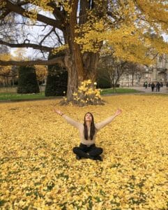 Viajera disfrutando del otoño mientras lanza flores al aire, capturando un momento mágico