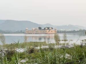 Vista del templo de Jaipur en el agua, rodeado por un paisaje sereno y pintoresco, destacando su arquitectura tradicional india y el entorno natural que lo rodea