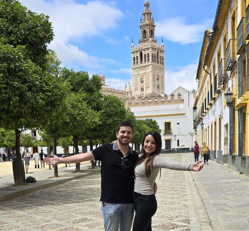 pareja-viajera-en-sevilla-disfrutando-de-la-ciudad Pareja de viajeros explorando Sevilla, España, disfrutando de su arquitectura histórica, plazas pintorescas y el ambiente vibrante de la ciudad