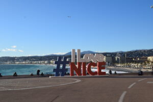 Cartel I Love Nice en Niza, Francia, con vista al paseo marítimo y el mar Mediterráneo, un punto fotográfico icónico para turistas que visitan la Riviera Francesa